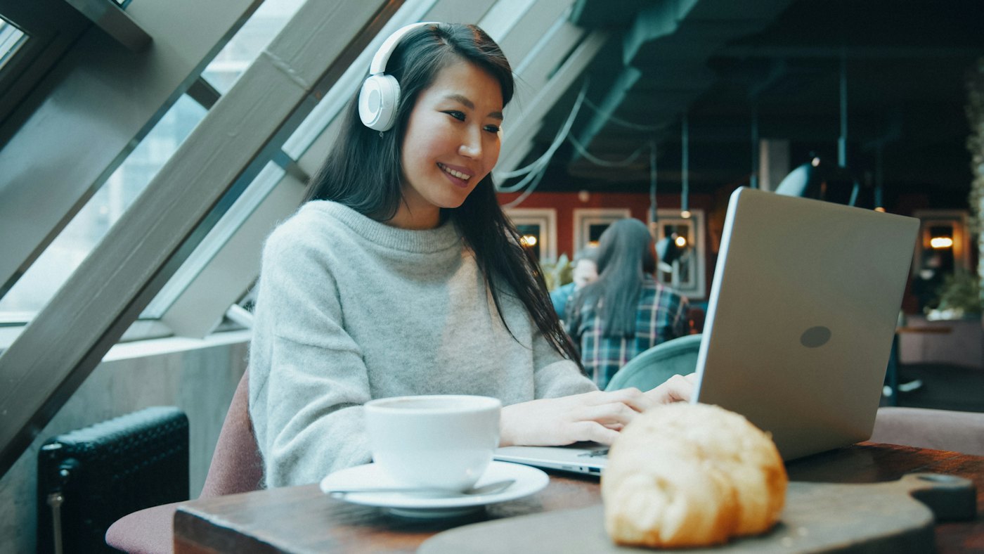 Frau mit Kopfhörern im Videocall am Laptop